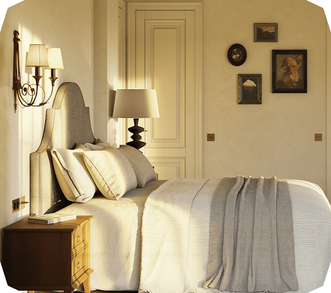 Cozy bedroom with a beige upholstered headboard, soft pillows, a textured blanket, wooden nightstand with a book, wall-mounted lamps, and framed artwork on the wall.