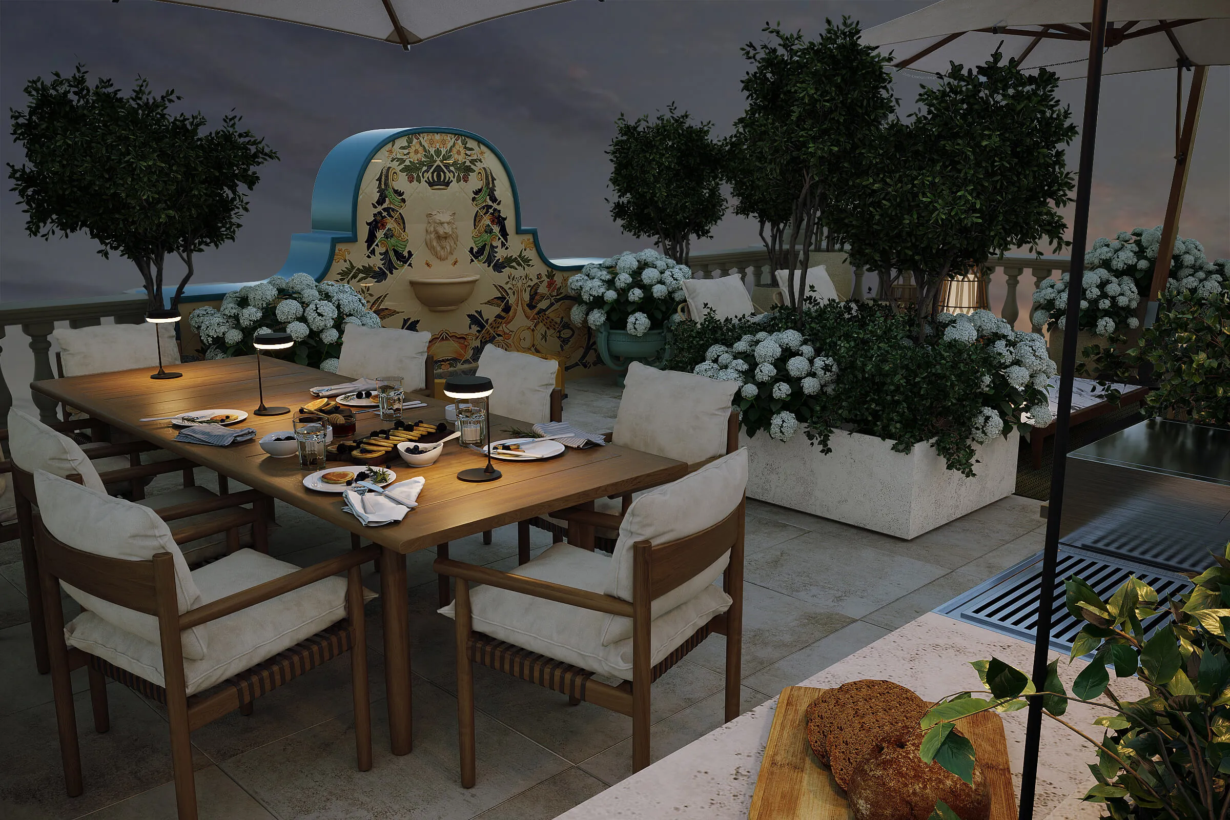 Penthouse Terrace — Zurich. Outdoor dining area at dusk with a wooden table set for dessert, surrounded by cushioned chairs, white hydrangea plants, and a decorative water fountain wall.